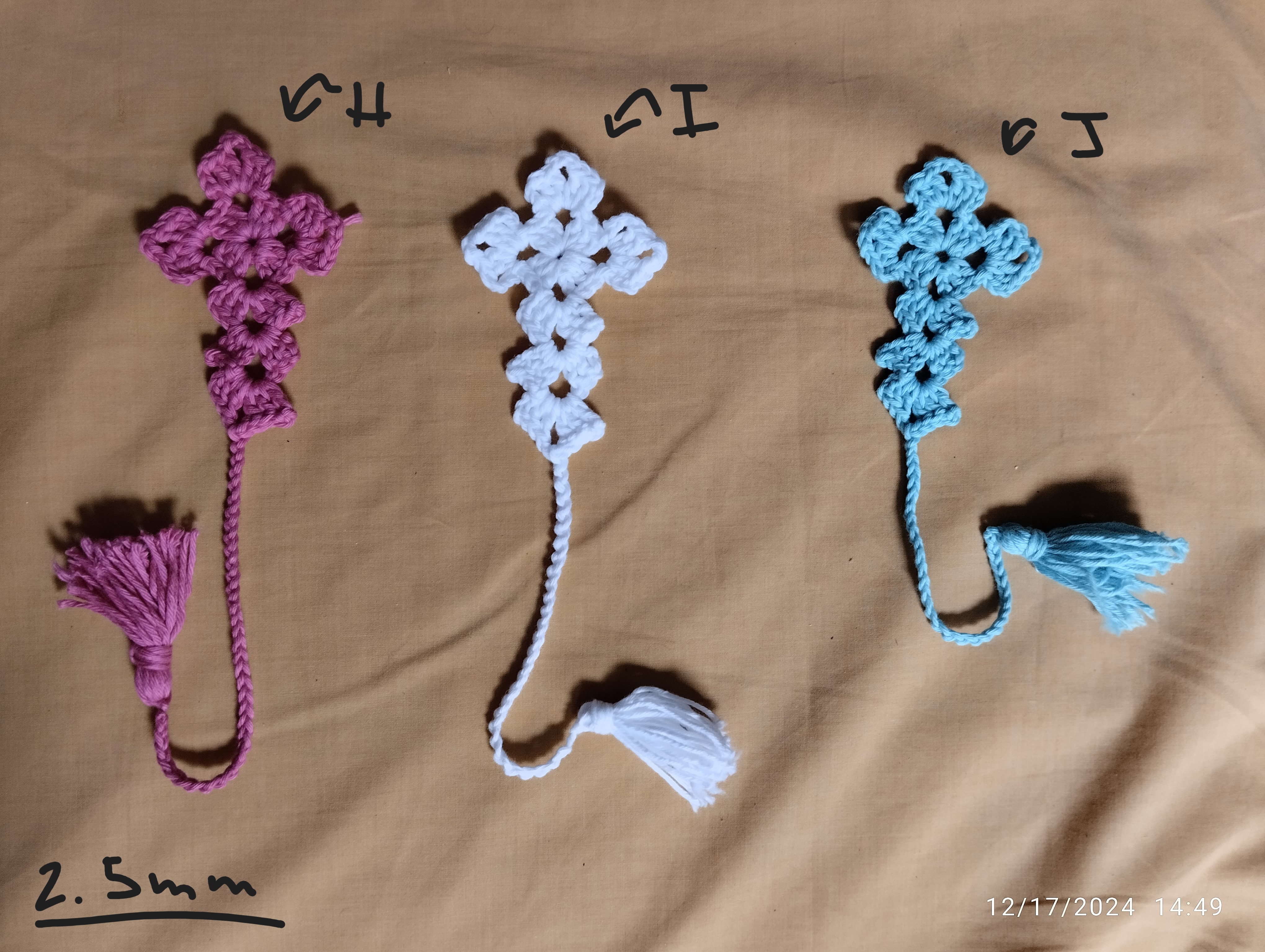 a set of three crochet crosses each with a tassel.